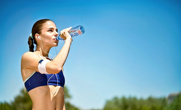 Девушка пьёт воду на пробежке